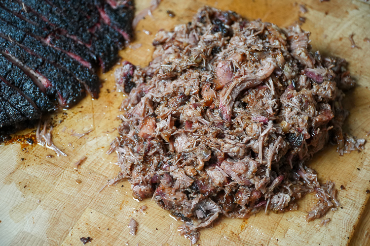 sauced chopped brisket on a wooden chopping board