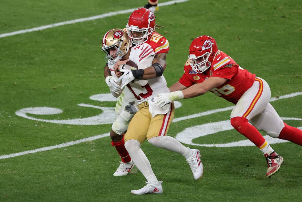  George Karlaftis #56 and Justin Reid #20 of the Kansas City Chiefs tackle Brock Purdy #13 of the San Francisco 49ers in the first half during Super Bowl LVIII at Allegiant Stadium on February 11, 2024 in Las Vegas, Nevada. 
