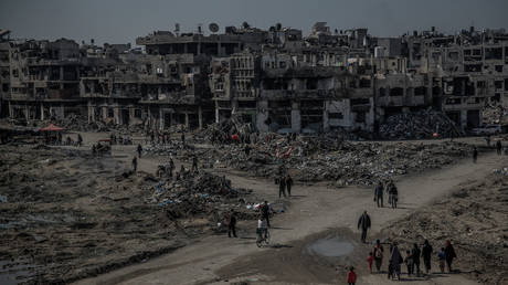 FILE PHOTO: Palestinians walking next to bombed buildings in Gaza City, 11 February, 2024.