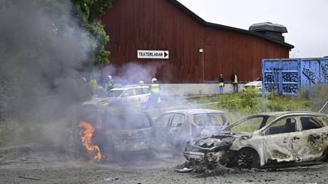 Police stand near the gutted remains of cars, at the Eritrean cultural festival "Eritrea Scandinavia" in Stockholm, August 3, 2023.