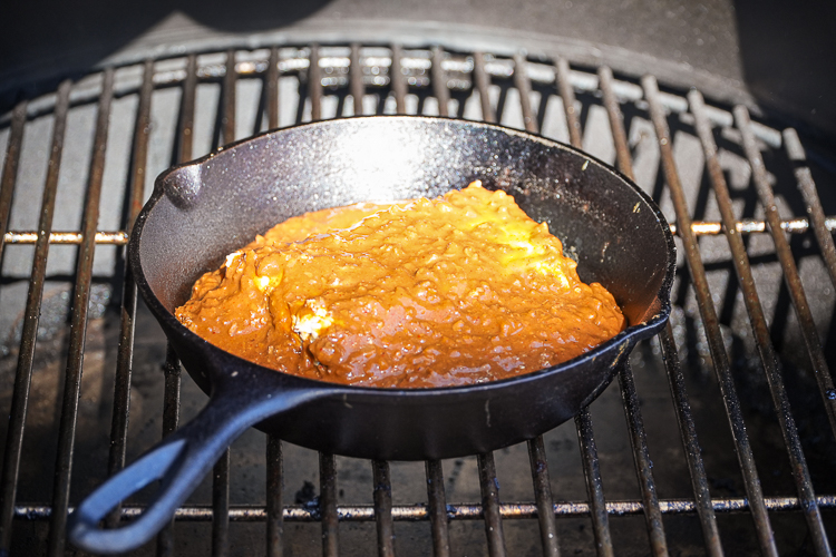 skillet with cream cheese and chili in the smoker cooking