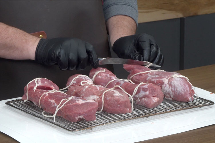 four pork tenderloins each tyed up with string