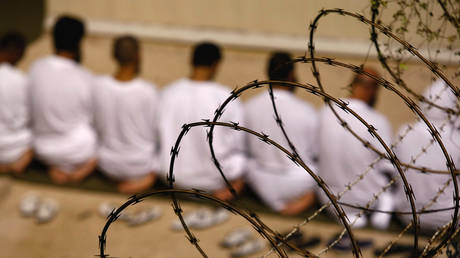 A group of detainees kneels during an early morning Islamic prayer in their camp at the U.S. military prison for "enemy combatants" on October 28, 2009 in Guantanamo Bay, Cuba