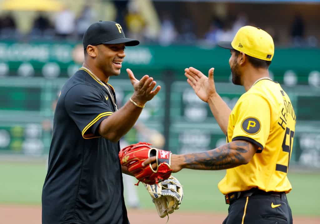 Russell Wilson of the Pittsburgh Steelers reacts with Raúl Hernández #90 of the Pittsburgh Pirates after throwing out the first pitch before the game against the Boston Red Sox at PNC Park on April 19, 2024 in Pittsburgh, Pennsylvania.