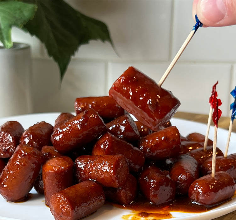 hot dog burnt ends on a white plate with toothpicks