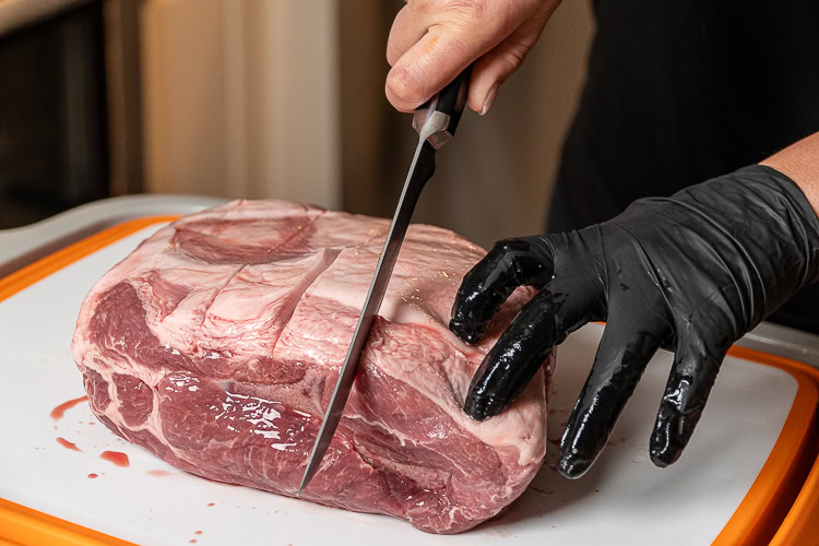 slicing into the raw fat cap of a piece of pork butt