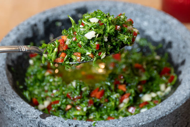 a spoonful of chimichurri over a bowl of chimichurri