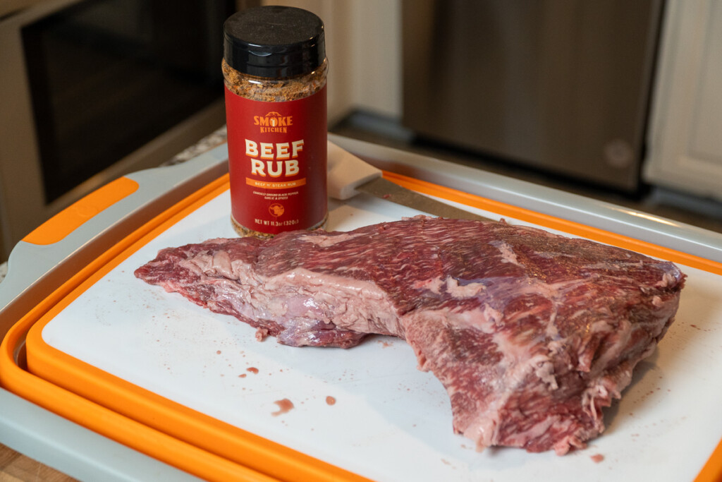 a piece of tri-tip and a bottle of beef rub on a white board