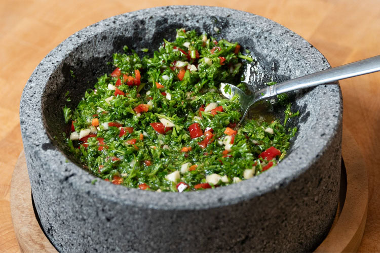 a bowl of chimichurri with a spoon in it