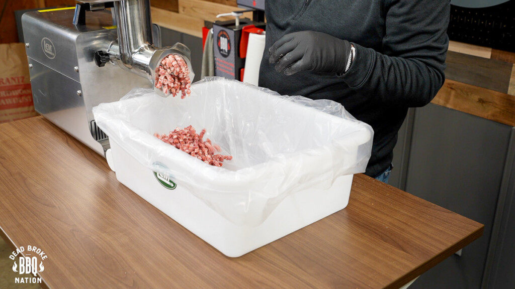 meat being extruded from the grinder in a white tub