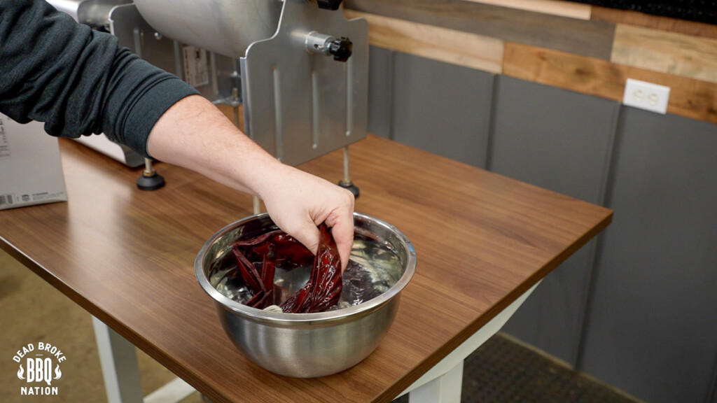 a hand mixing sausage casings in a metal bowl