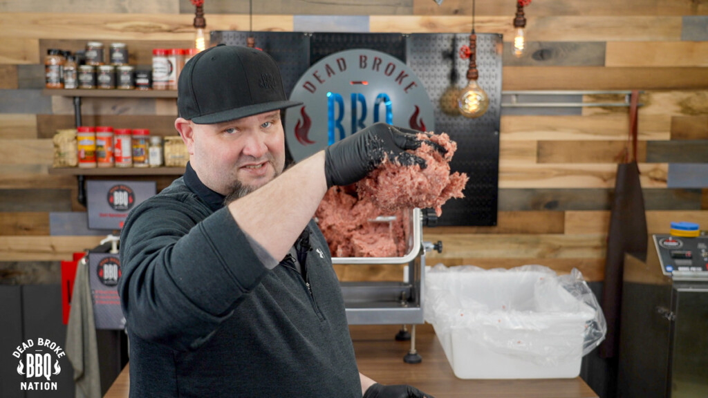 a man holding his hand in the air with sausage meat stuck to it