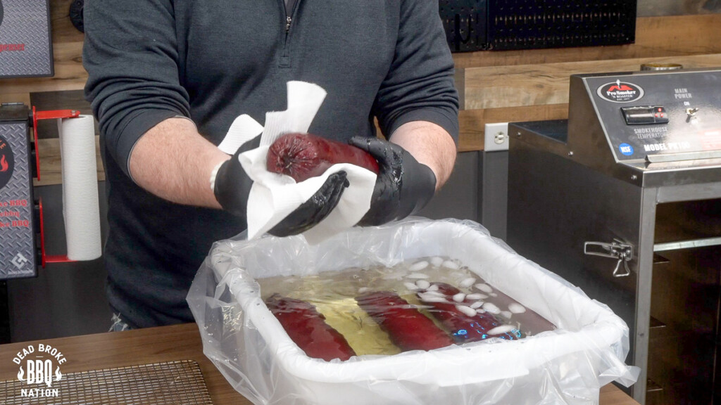 a man drying off a summer sausage after its come out of a waterbath