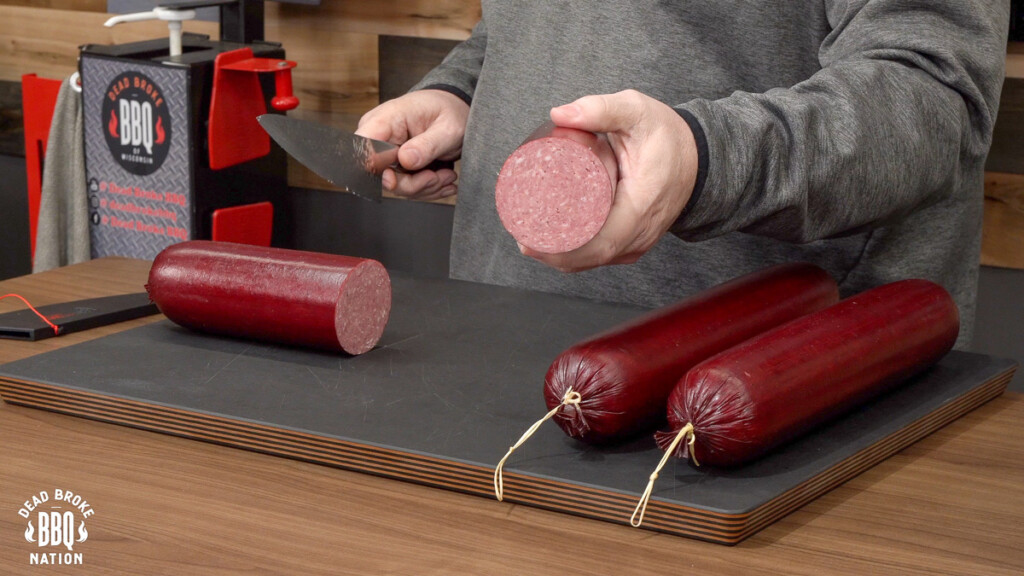 a hand holding a chubb of summer sausage