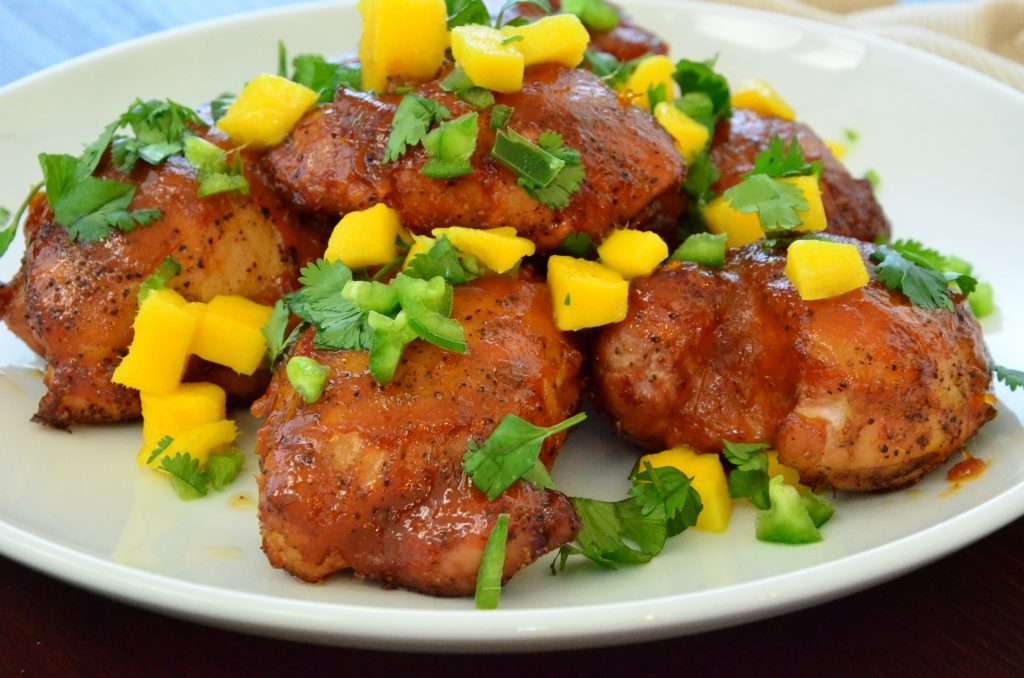 Mango-Jalapeno chicken breasts on white plate with chopped mango and cilantro