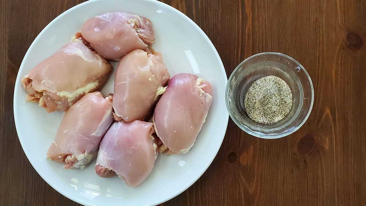 Raw chicken thighs on plate with bowl of rub