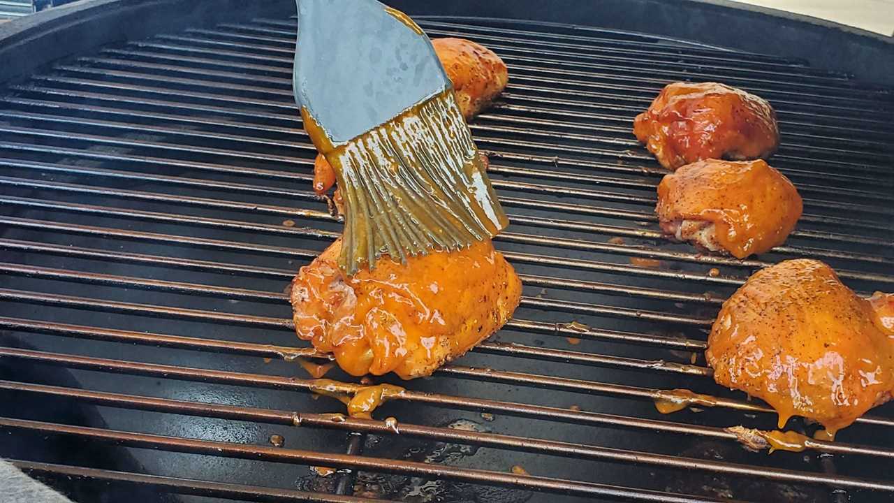 Applying BBQ sauce to boneless chicken thighs