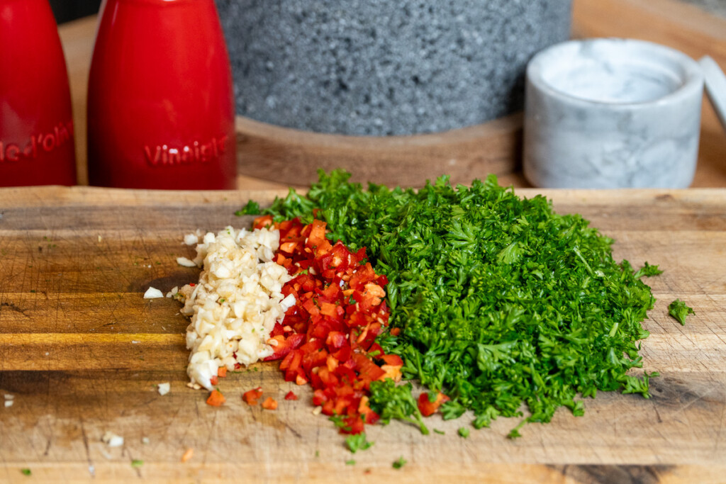chopped garlic, red jalapeno and parsley on a wooden chopping board