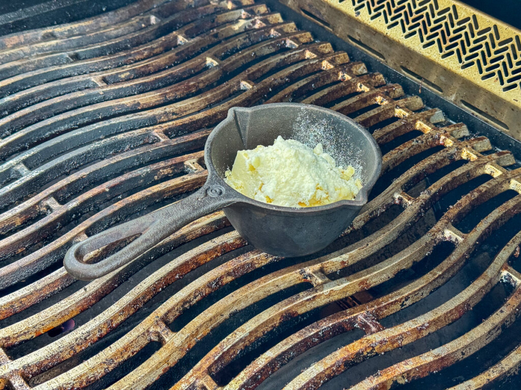 cast iron pot on the grill with butter, parmesan and garlic in it