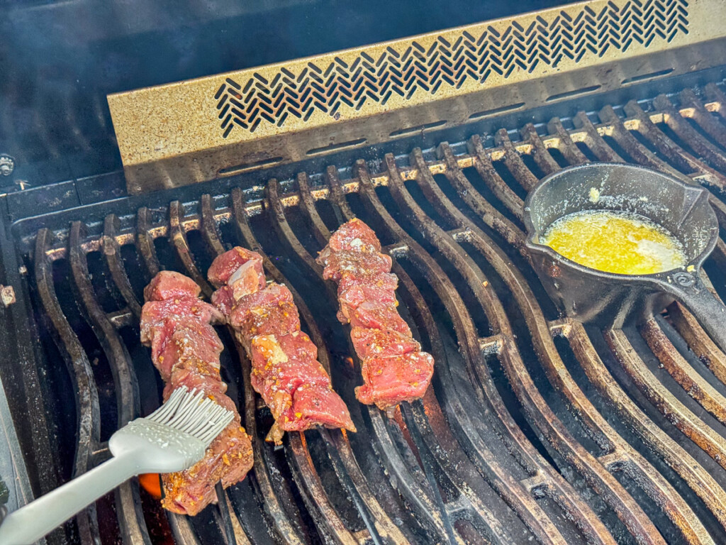 basting raw sirloin tip skewers on the grill
