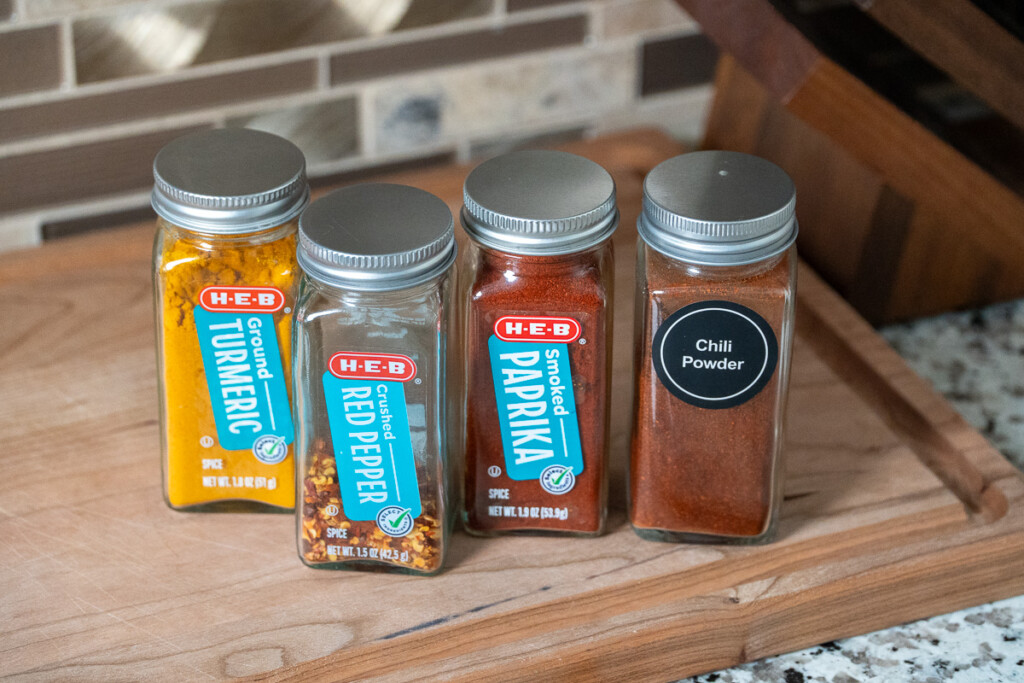 four jars of spices on a wooden board