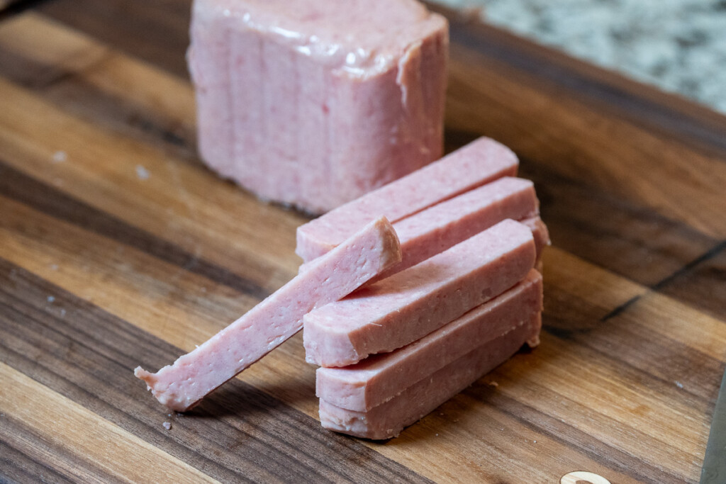 unsmoked spam sliced into fry shapes on a wooden board