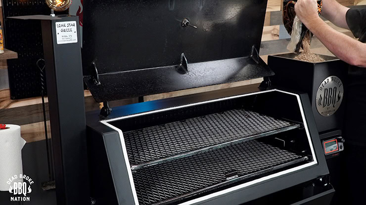 Lone Star Grillz Pellet Grill with an open lid and a person dumping pellets into the pellet hopper