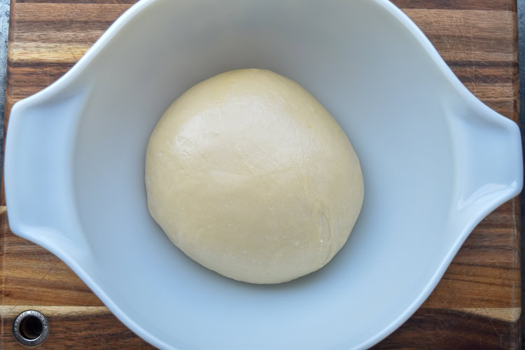 a ball of brioche dough in a white bowl 