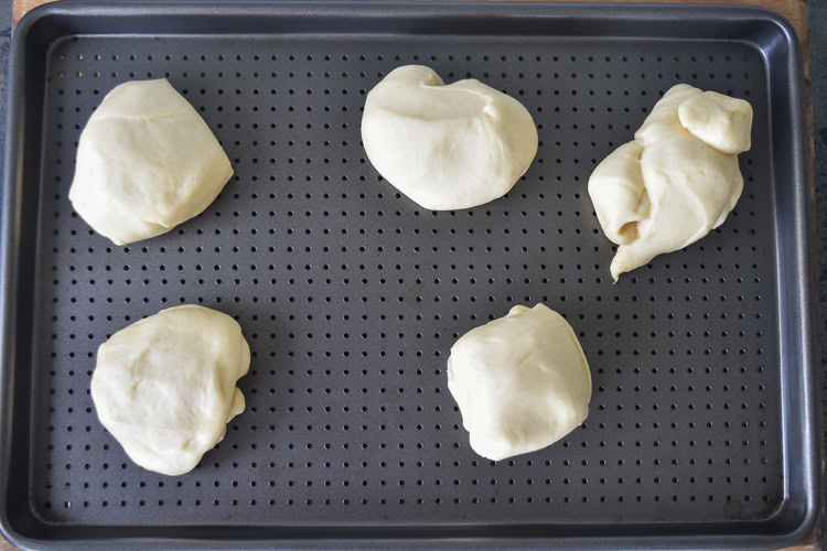 pieces of brioche dough on a baking tray with small holes