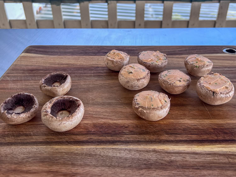 stuffed and unstuffed raw mushrooms on a wooden board