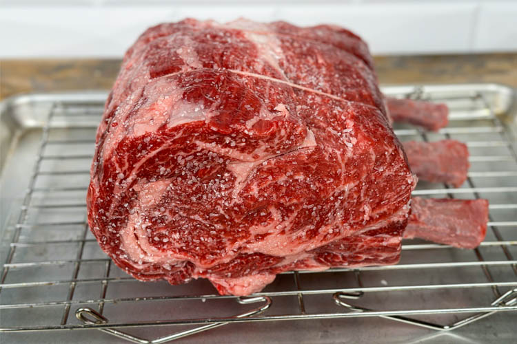 prime rib with Kosher salt sprinkled on it sitting on a wire rack