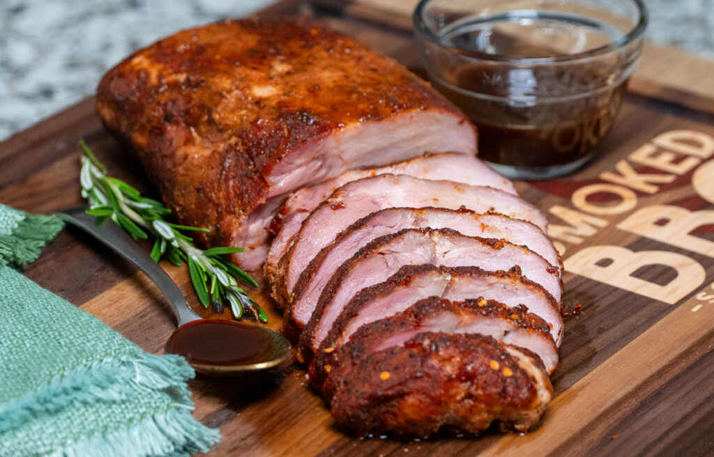 a sliced piece of cooked pork loin on a wooden board