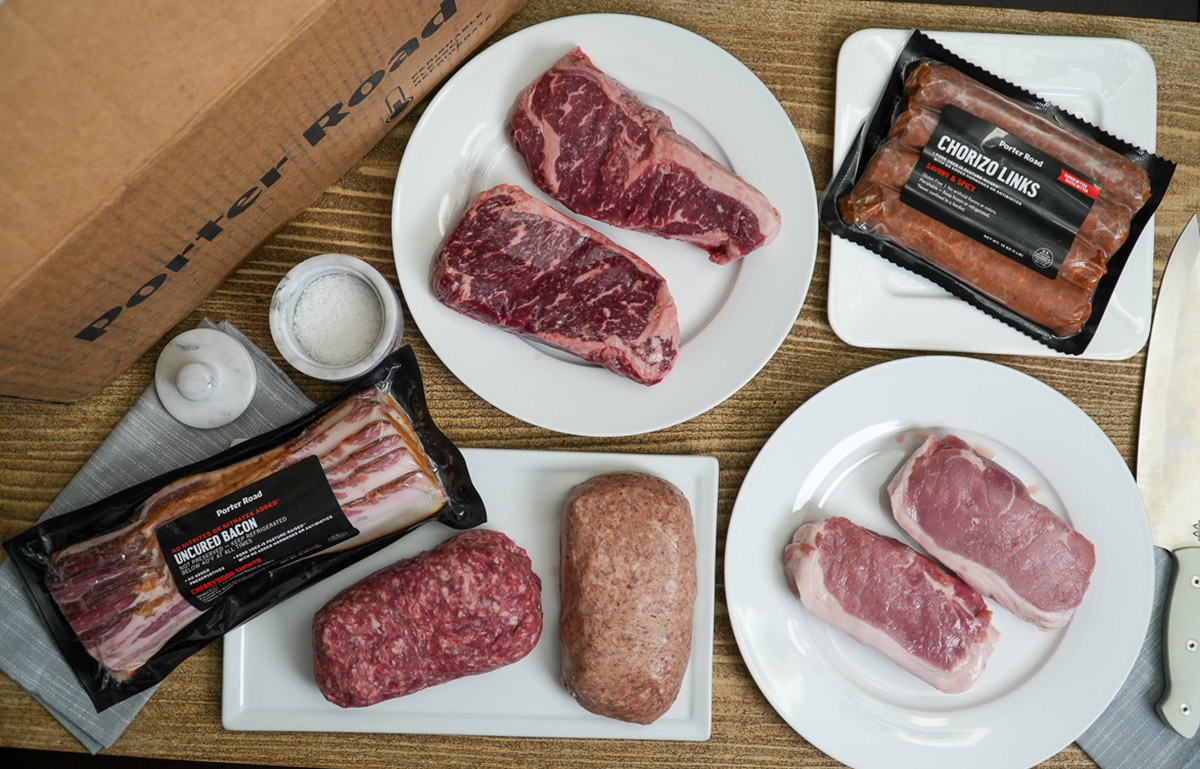 selection of meat from porter road including steak, pork chops, ground beef, chorizo links and bacon on a table