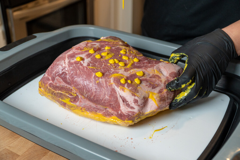 dots of mustard on a raw pork butt