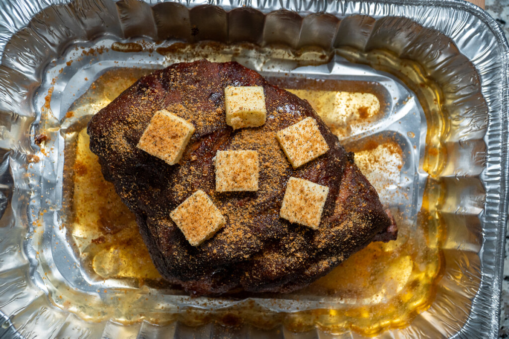 cooked pork but in aluminum tray with apple juice and butter pats 