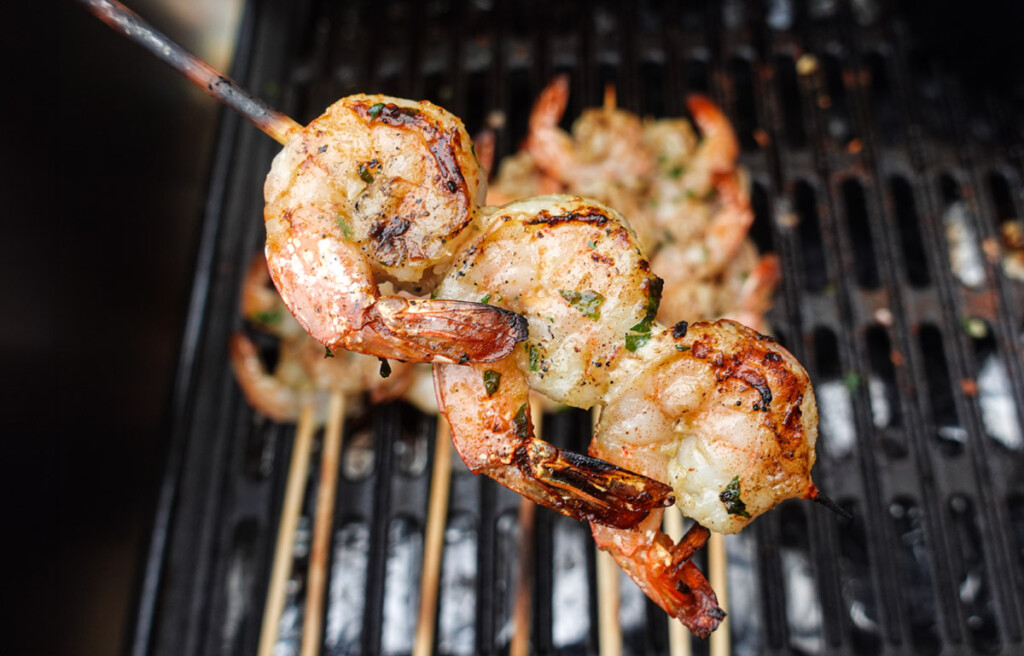 grilled shrimp on bamboo skewer held over charcoal grill