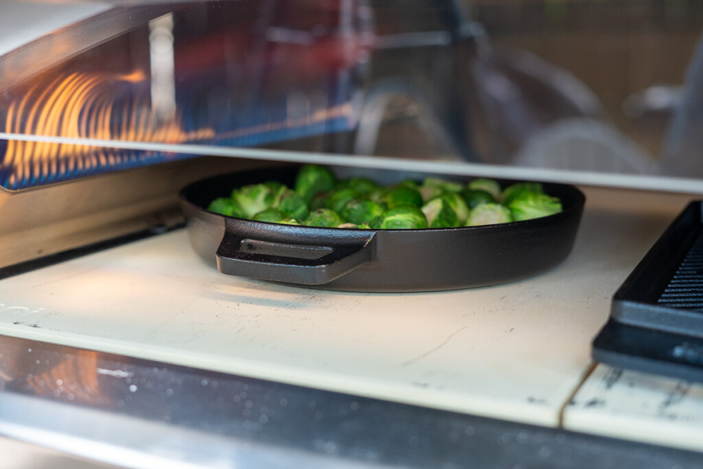 brussels sprouts cooking in a cast iron skillet in Oni Koda 2 Max pizza oven