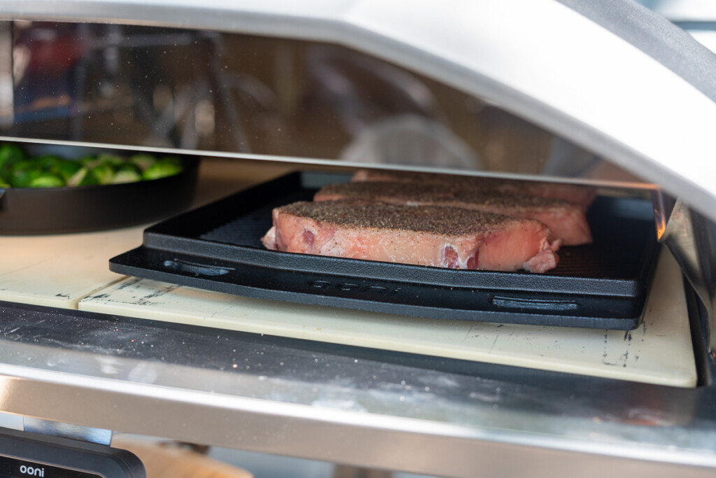 steaks cooking on a roasting pan in Ooni Koda 2 Max pizza oven