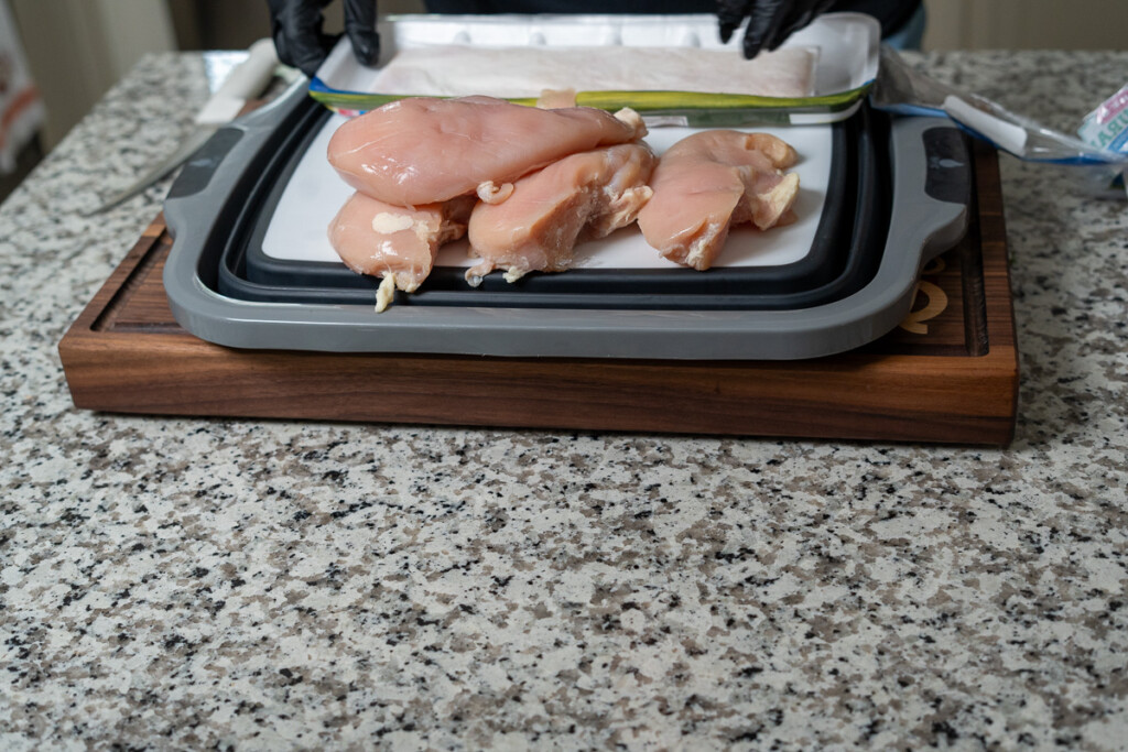 raw chicken breasts on a white board