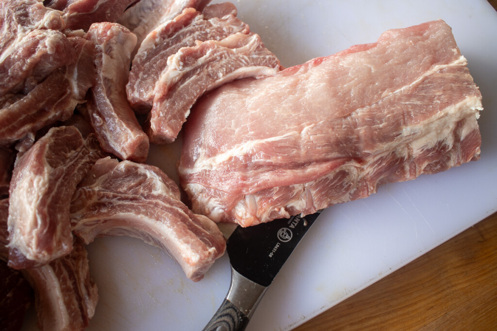 raw baby back ribs being cut being cut up on a white board