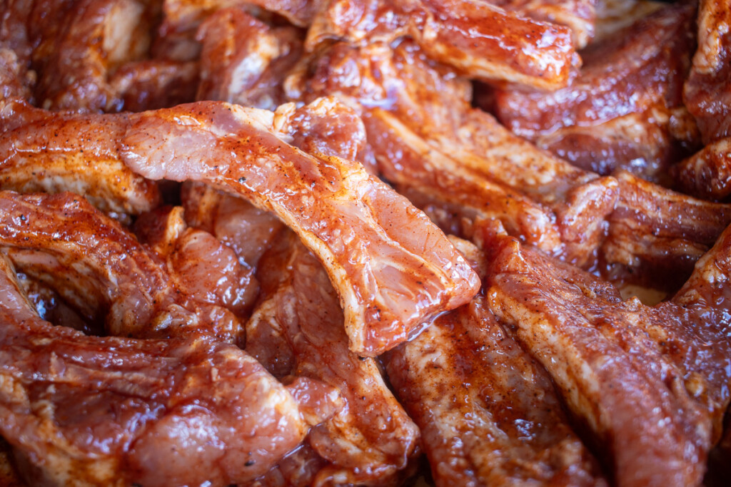 raw baby back ribs covered in BBQ sauce