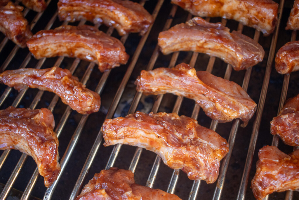 raw sauced and seasoned party ribs on the grill