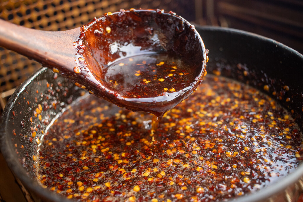 a wooden spoon with hot honey sauce dripping off it