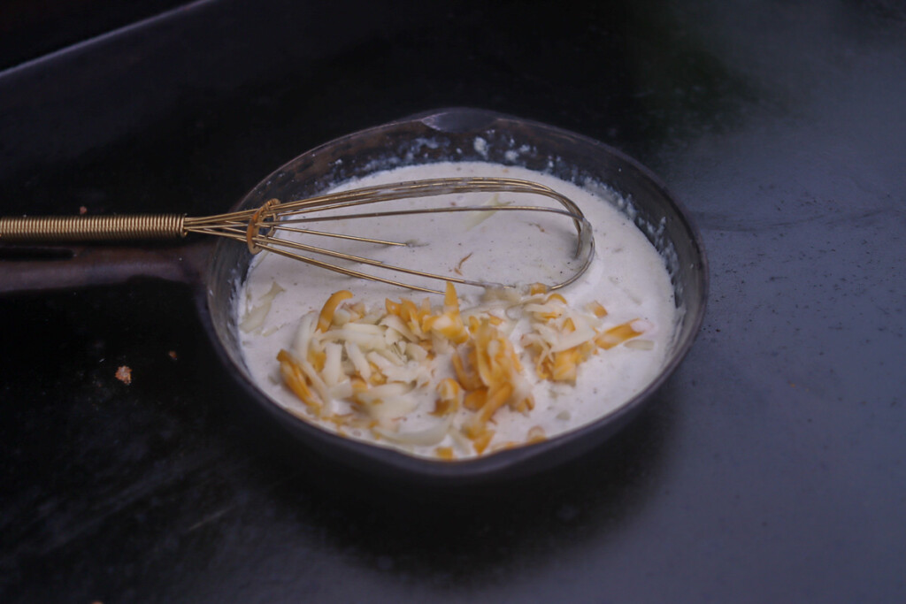 queso sauce with the cheese added being stirred with a whisk