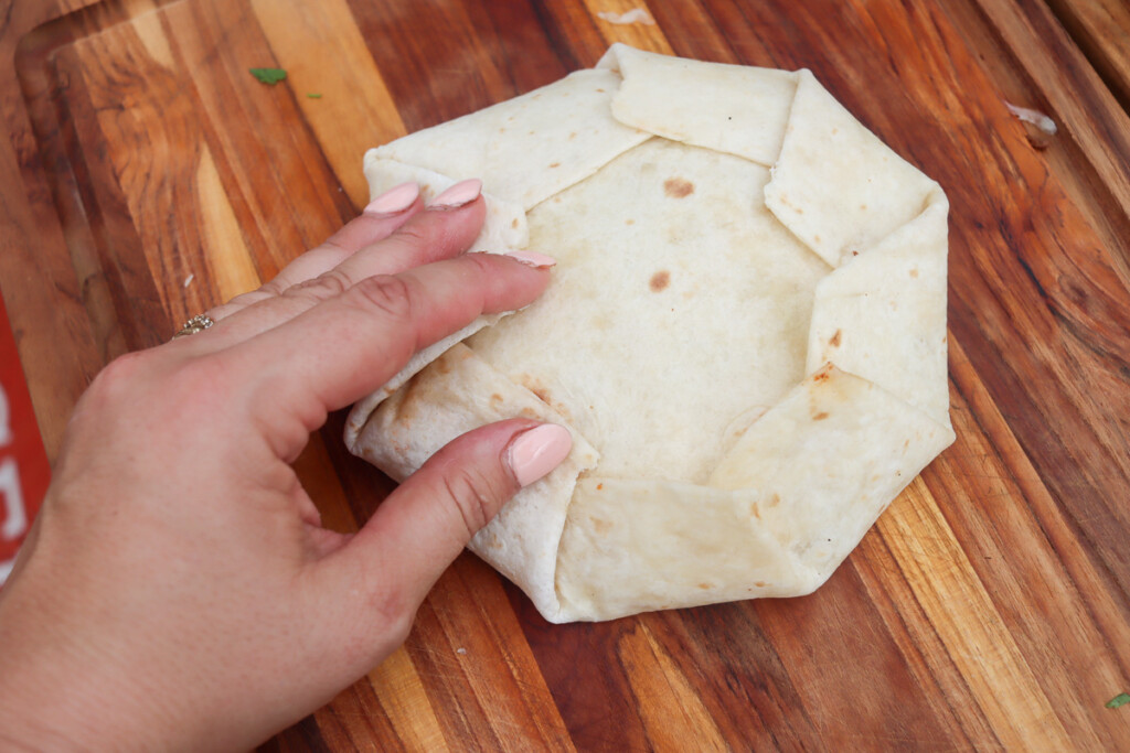 a hand foling the large flour tortilla into a parcel