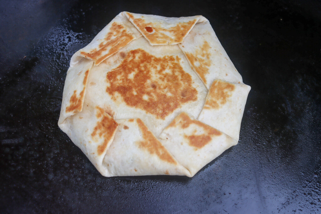 a crunchwrap cooking on the griddle