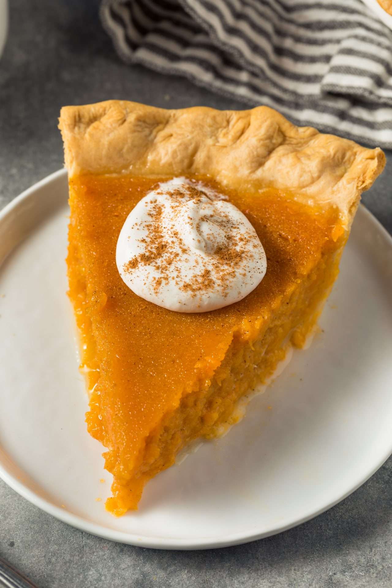 Slice of sweet potato pie with whipping cream on top