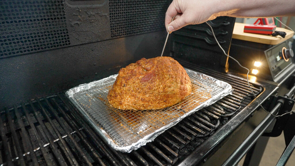 a seasoned ham with a probe sticking out of it