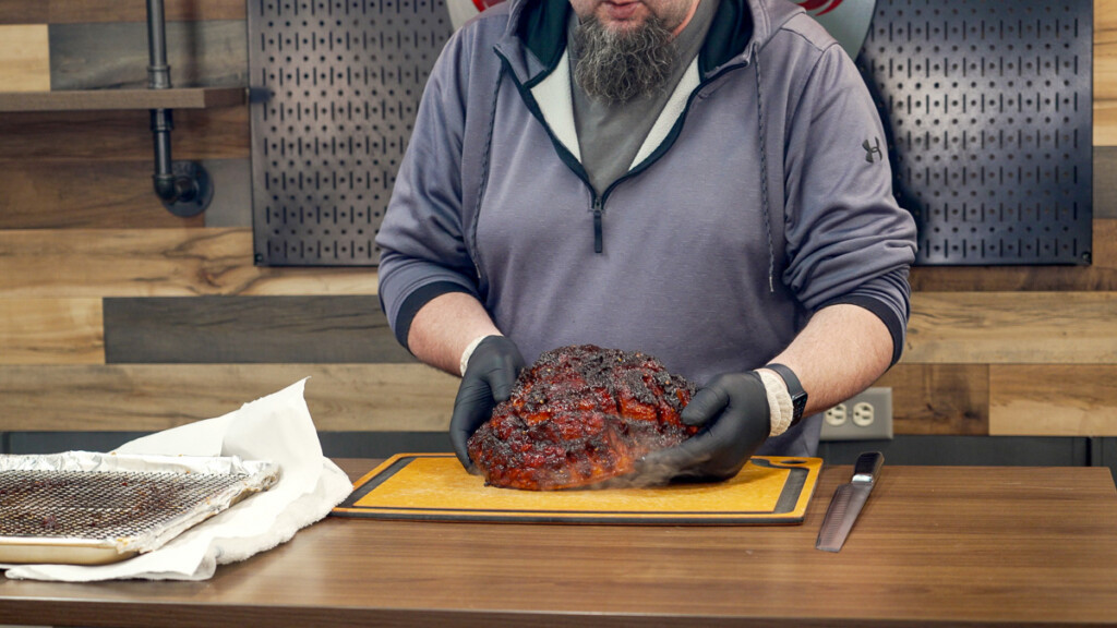 the finished smoked ham beomg placed on a wooden board