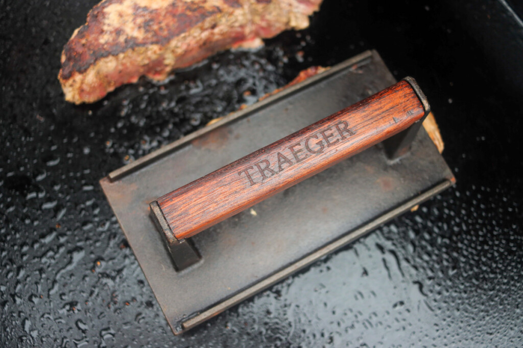 a cast iron weight on top of a steak